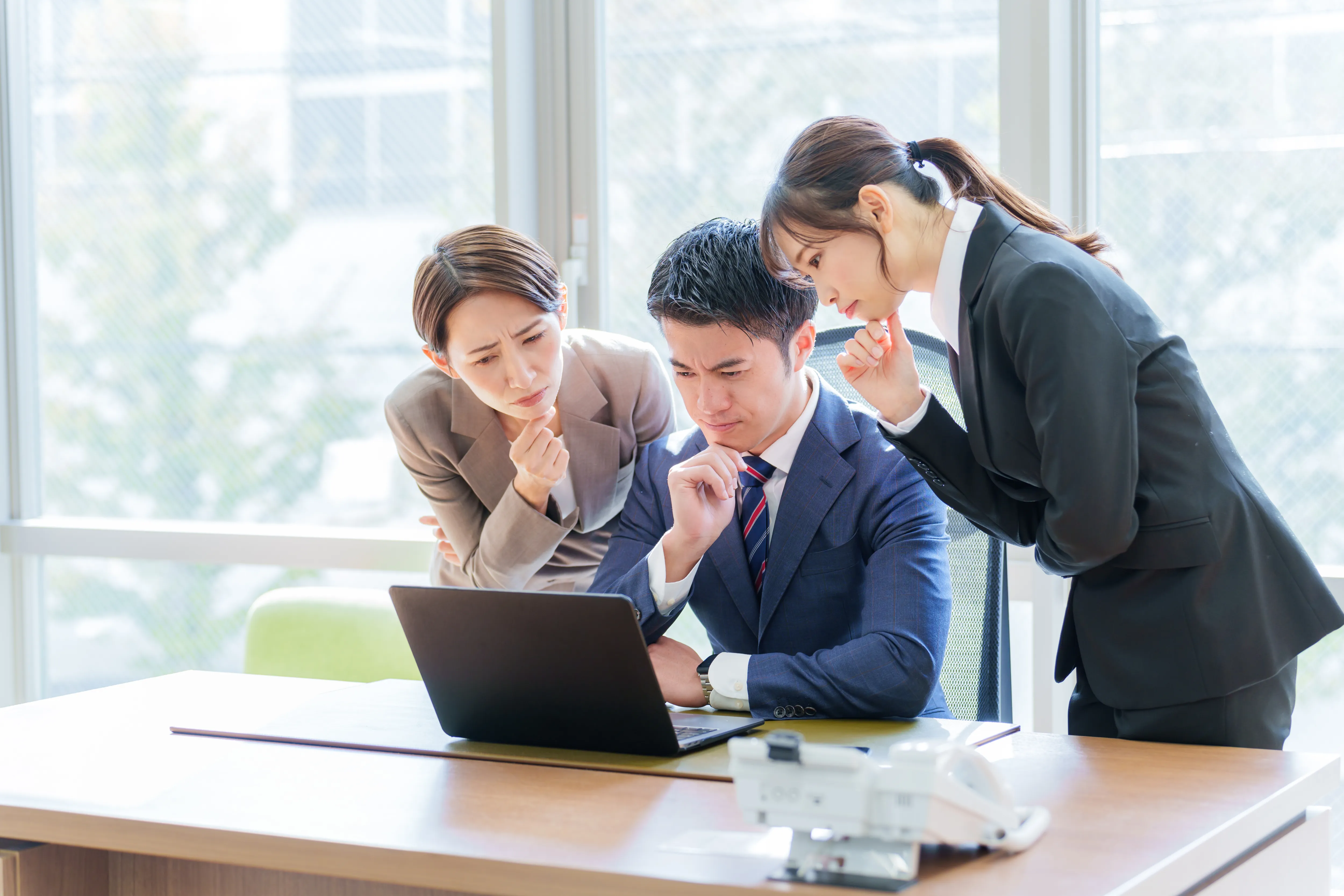 パソコンの画面を見て悩む社員